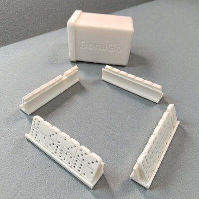 A compact, 3D-printed white travel case for DomiGo portable dominoes, showing the open lid and durable modular design.