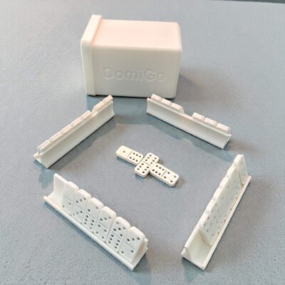 A compact, 3D-printed white travel case for DomiGo portable dominoes, showing the open lid and durable modular design.
